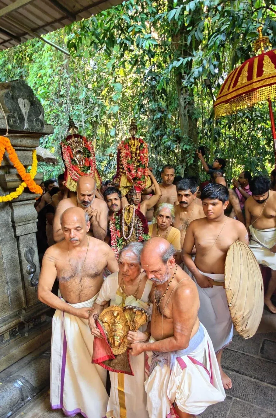 Aayilyam at Mannarasala: lamp-lit deities, Amma carrying the Nagaraja idol in procession, and the pooja over the rangoli